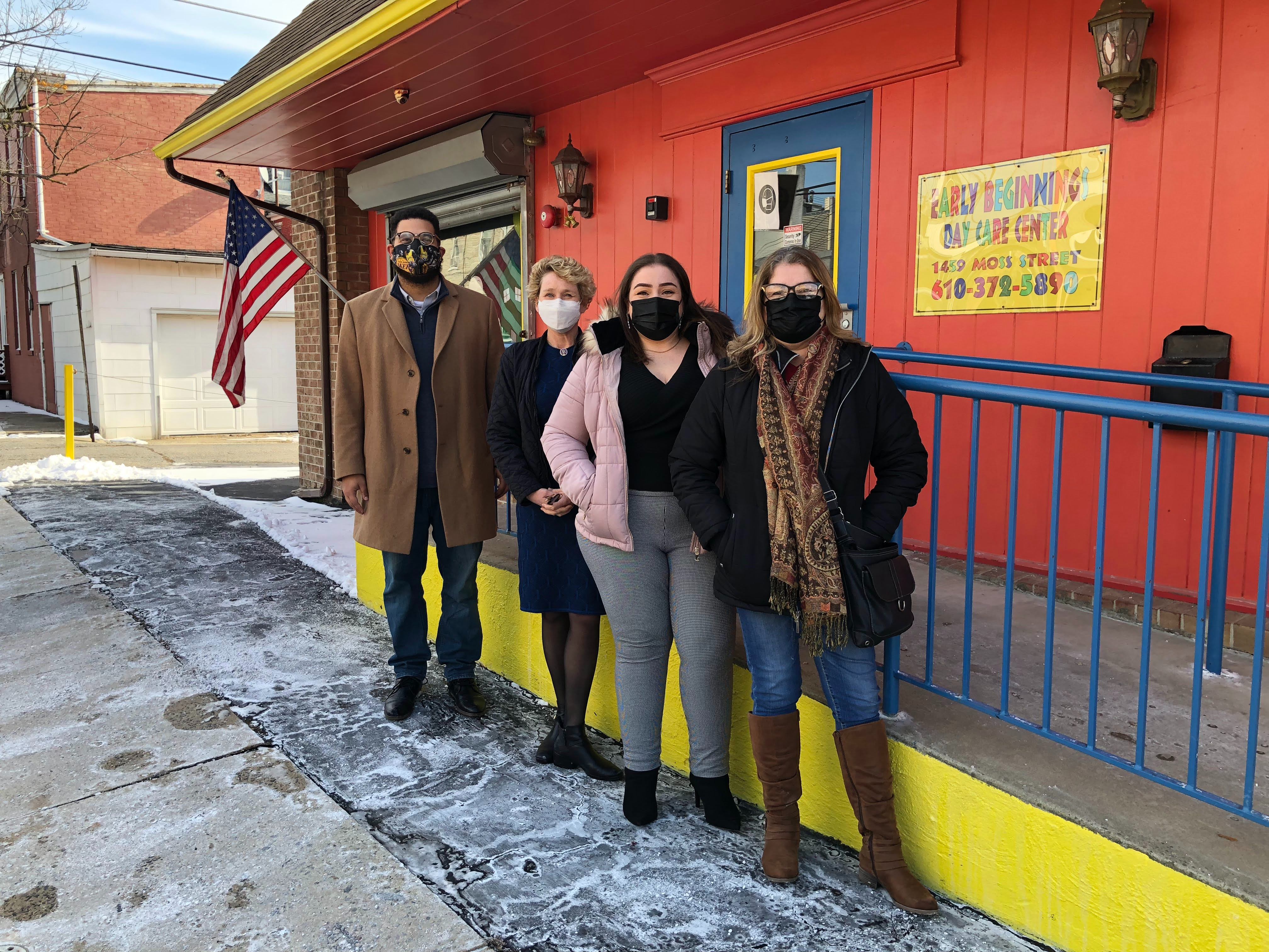 four people stand in front of a red building