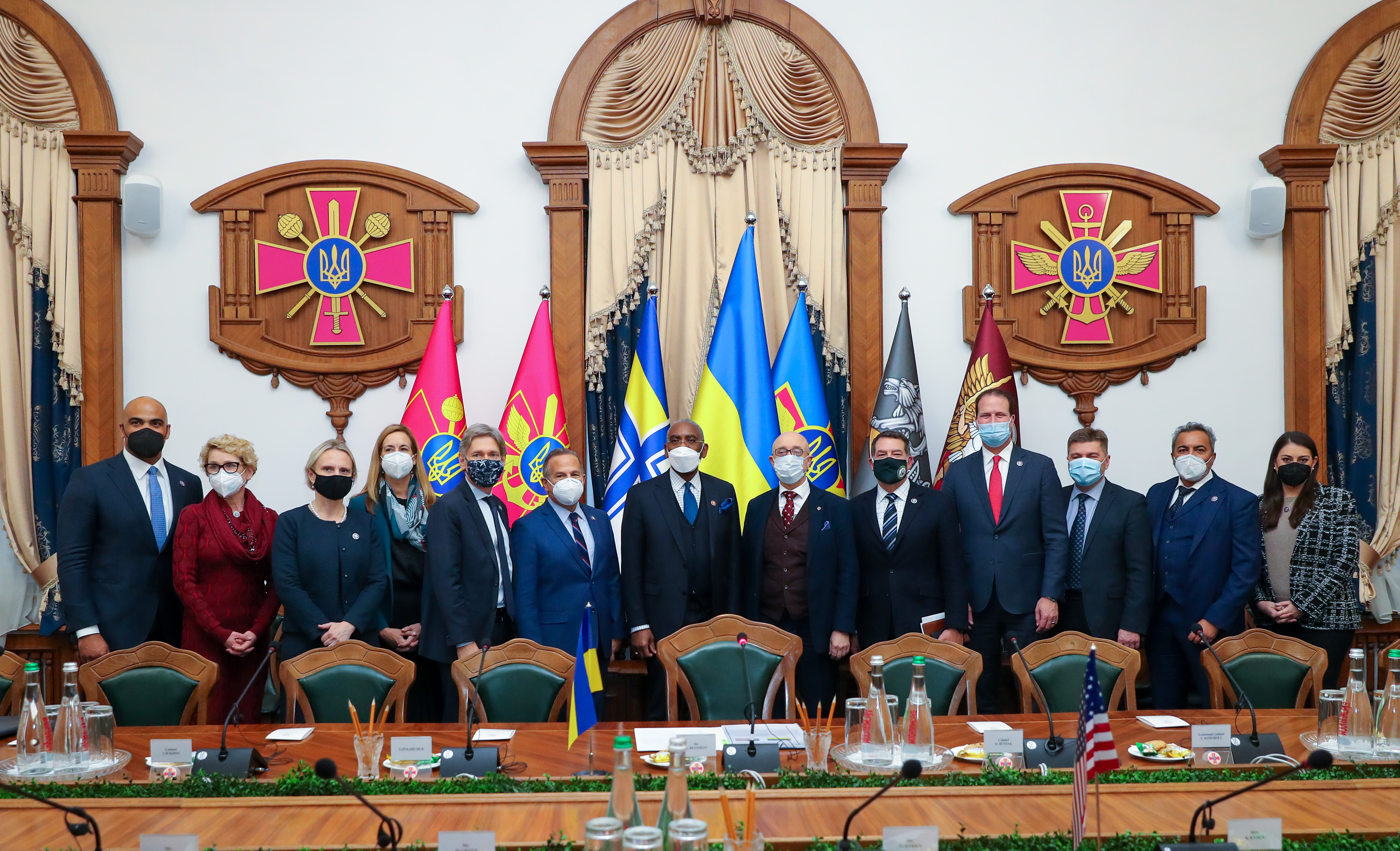 Several people pose in front of flags. 