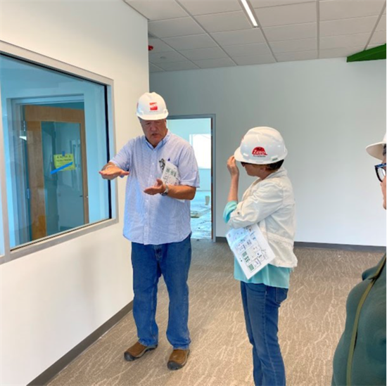 Rep. Houlahan wears a hard hat and stands next to a man in a hard hat