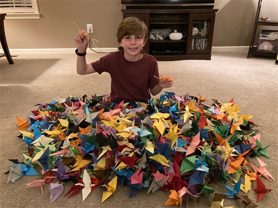 A child sits in a pile or origami cranes