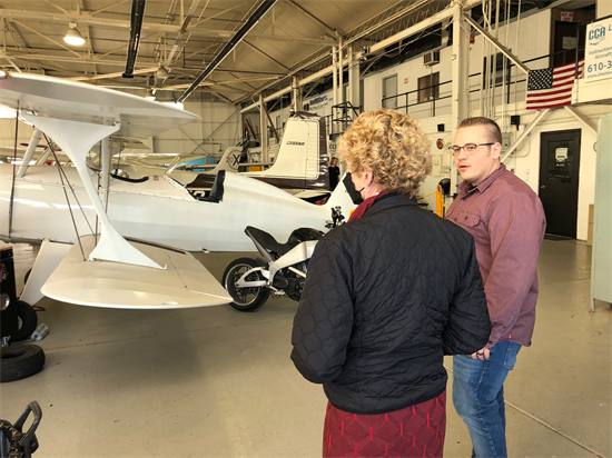 Two people stand in an airplane hangar